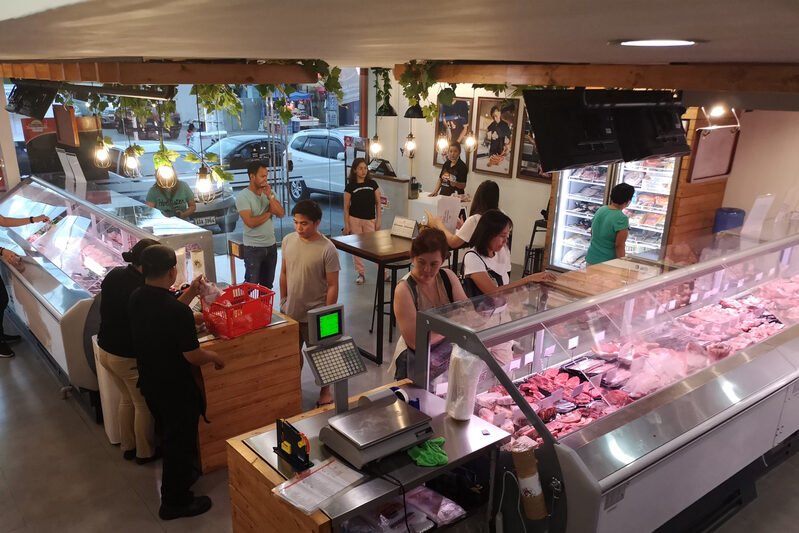 Inside the N.E Meatshop counter, staff serving customers at the meat cases