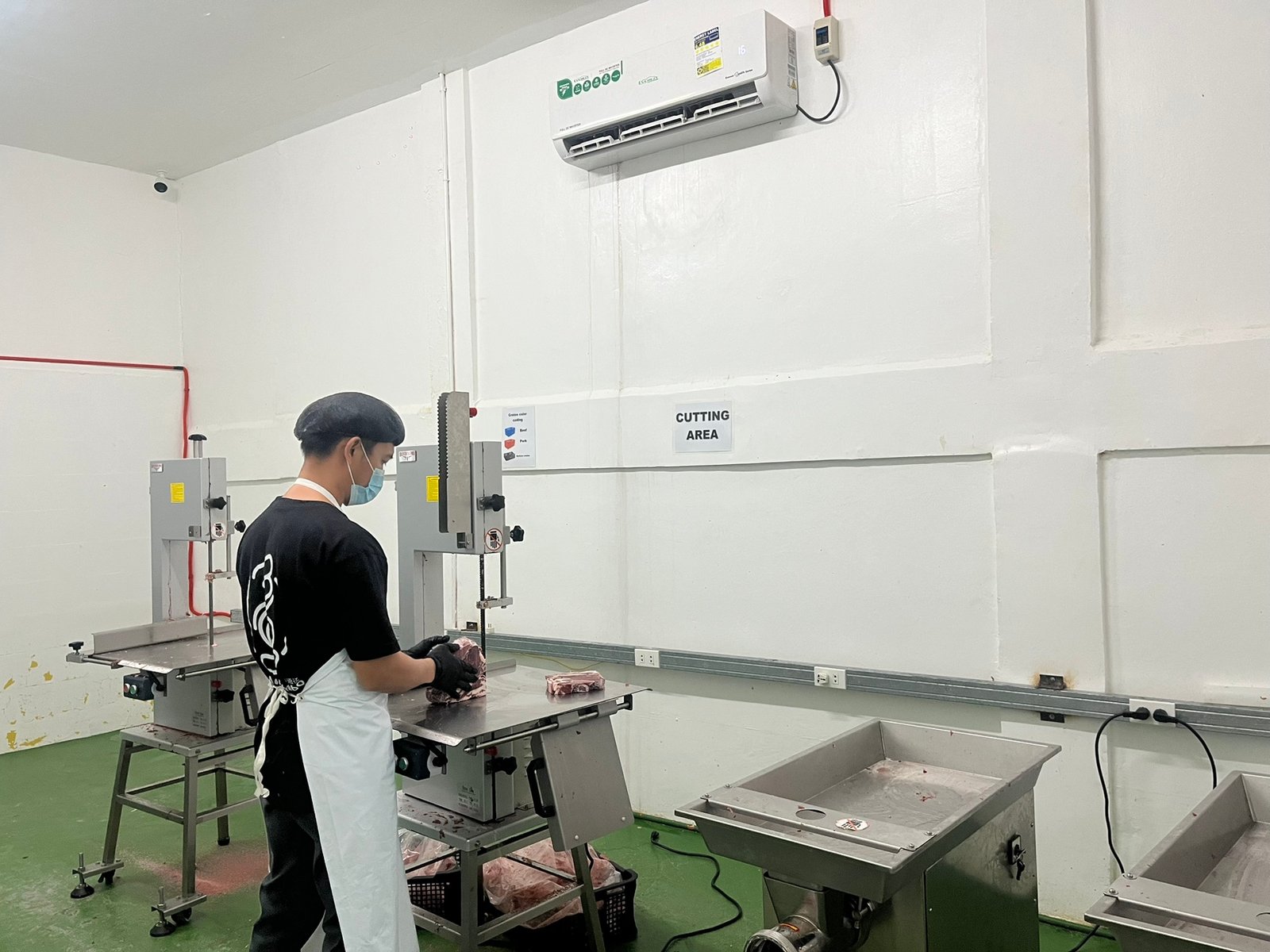 NE Meats butcher trimming a cut on the band saw